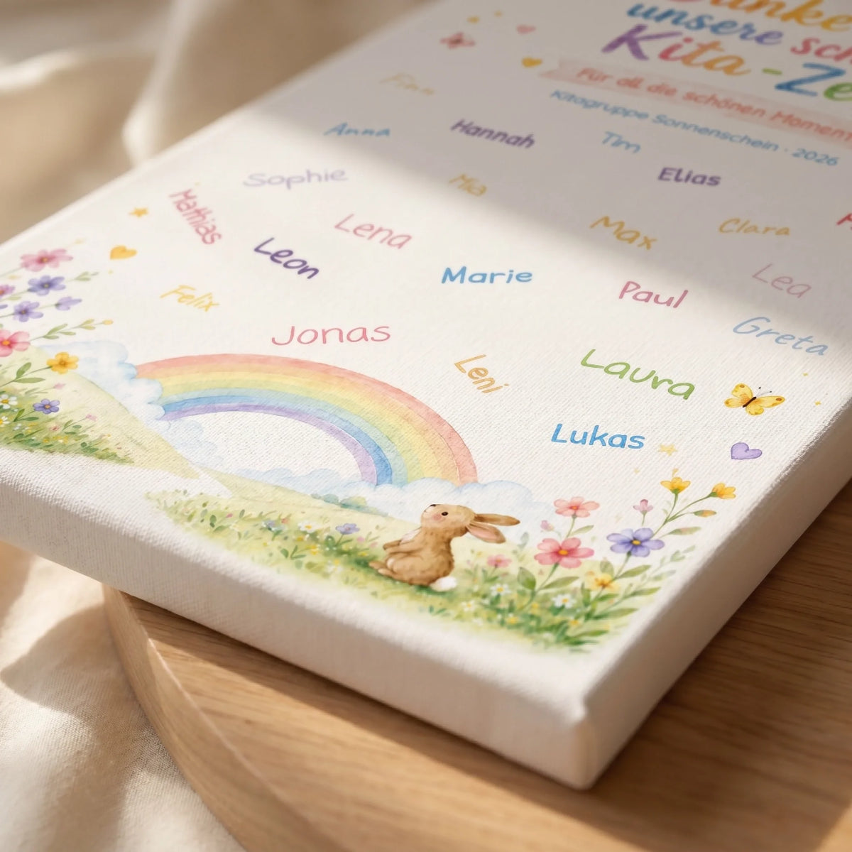 Gästebuch mit Regenbogen, Blumen und Namen wie Maria, Paul, Jonas, Elias auf weißem Stoff, auf Holz liegend - Feed